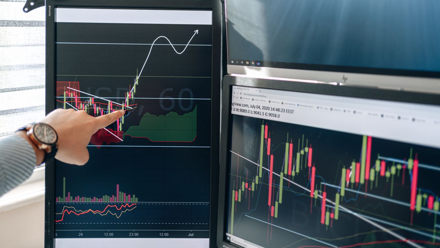 Trader analysing live market charts across multiple monitors